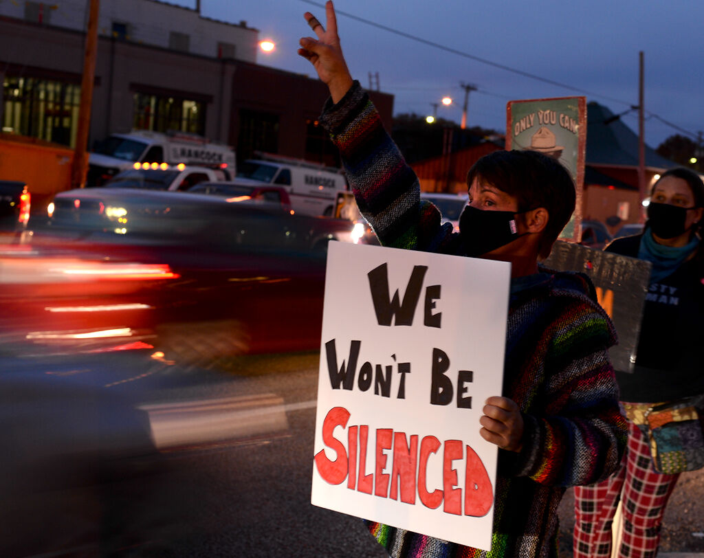 Bethany Hadley holds banner saying 'We Won't Be Silenced' while doing a peace sign on Wednesday at Providence and Broadway in Columbia.